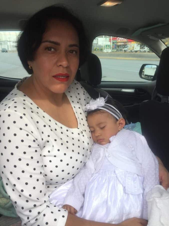 mama-despues-de-los-40-con-hija-concebida-via-fecundacion-fiv-dentro-de-un-coche-con-vestido-blanco-dia-de-bautizo